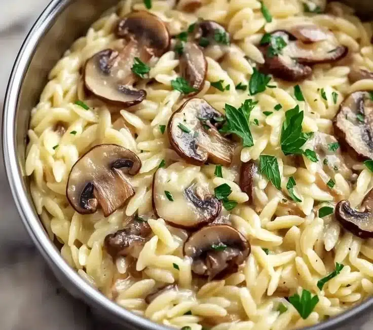 Creamy orzo with mushrooms served in a bowl, garnished with herbs.