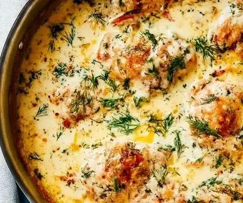 Creamy oven baked chicken thighs served with vegetables on a plate.