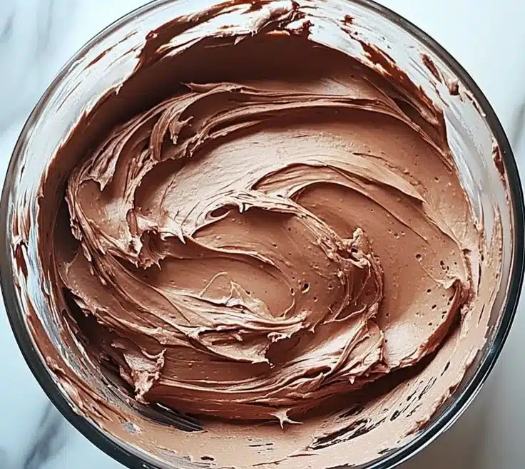 Bowl of decadent chocolate buttercream frosting ready for cake decorating