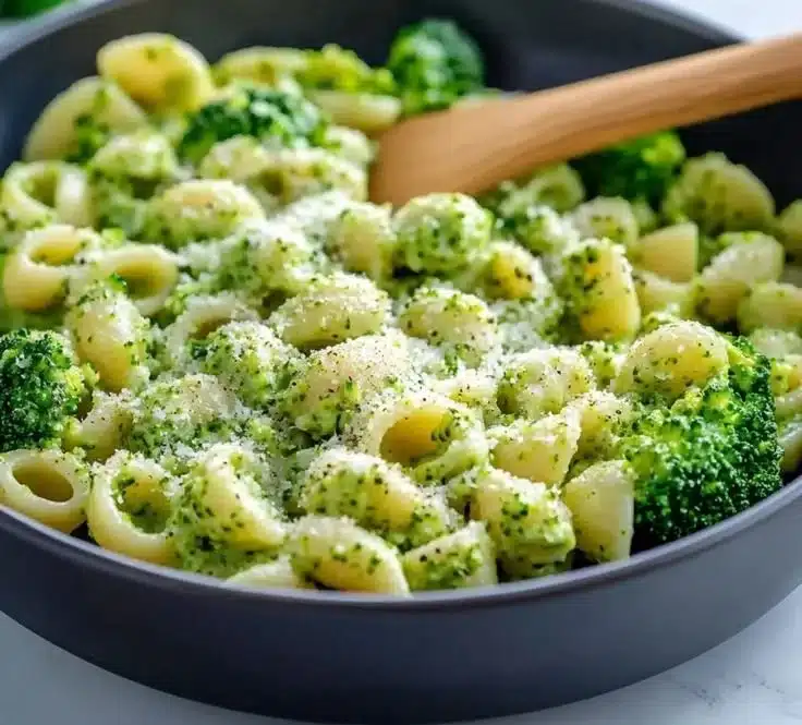 A plate of light and healthy broccoli pasta garnished with herbs and parmesan.