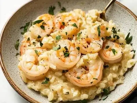 Plate of quick lemon garlic shrimp risotto garnished with parsley and lemon slices.