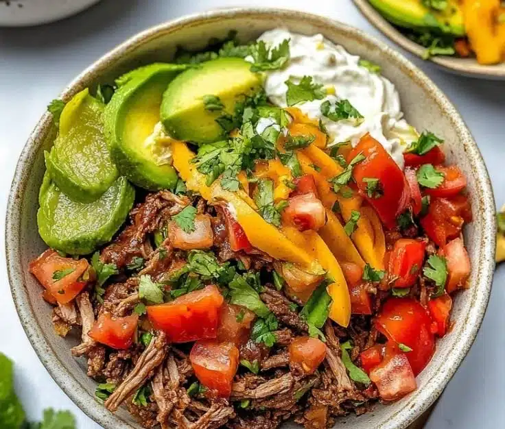Delicious slow cooker chipotle beef burrito bowls garnished with fresh ingredients