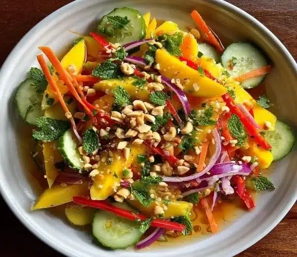 Fresh zesty Thai mango salad with colorful ingredients and herbs.