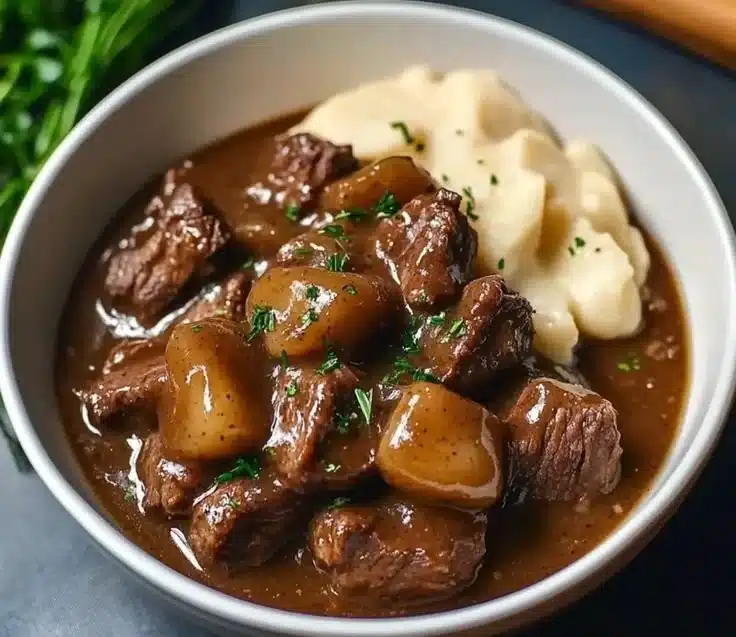Crock pot beef tips simmering in rich gravy, perfect for a cozy dinner.