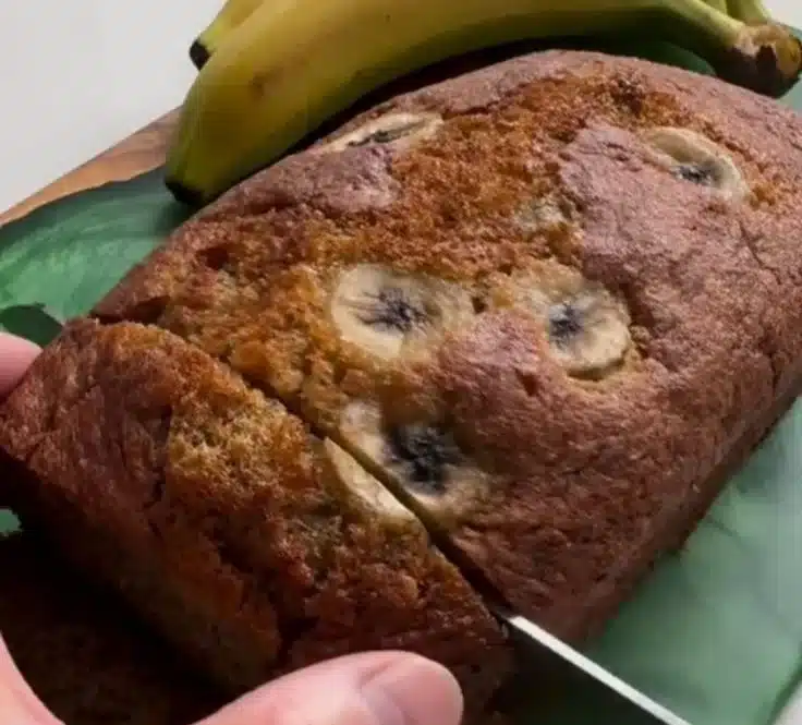 Moist banana cake without a mixer on a plate, garnished with bananas.