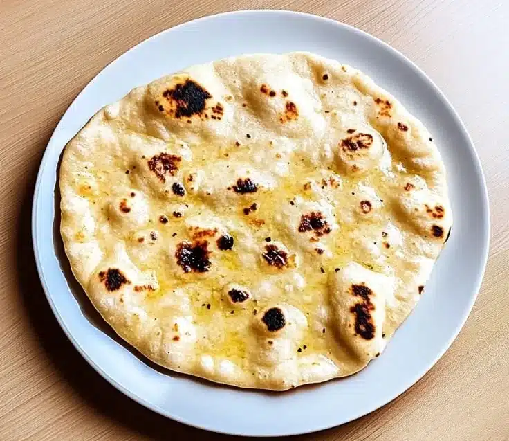 Fluffy cottage cheese naan bread served with herbs and spices on a wooden plate