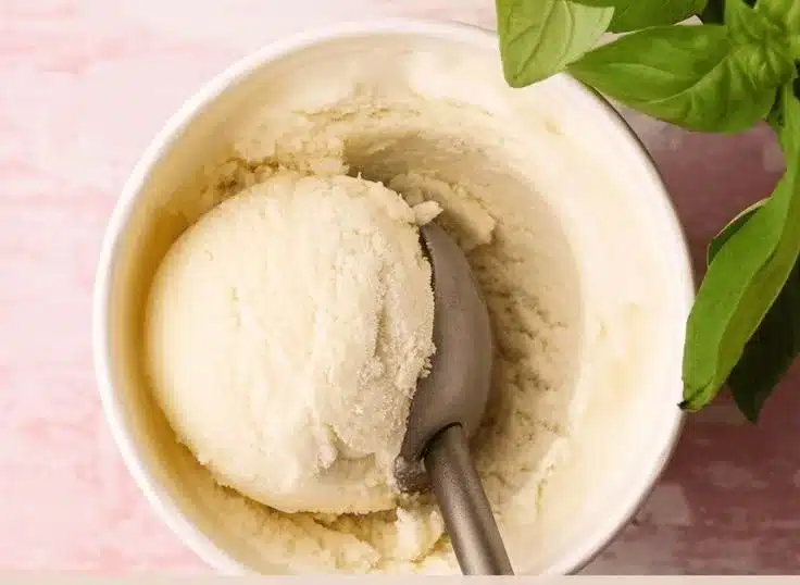 Homemade basil ice cream served in a bowl with fresh basil leaves