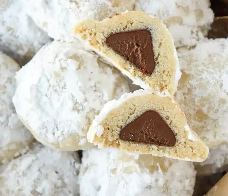 Snowball Kiss Cookies topped with chocolate and dusted with powdered sugar