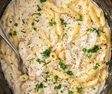 Crockpot Chicken Alfredo served in a bowl with a creamy white sauce and garnish